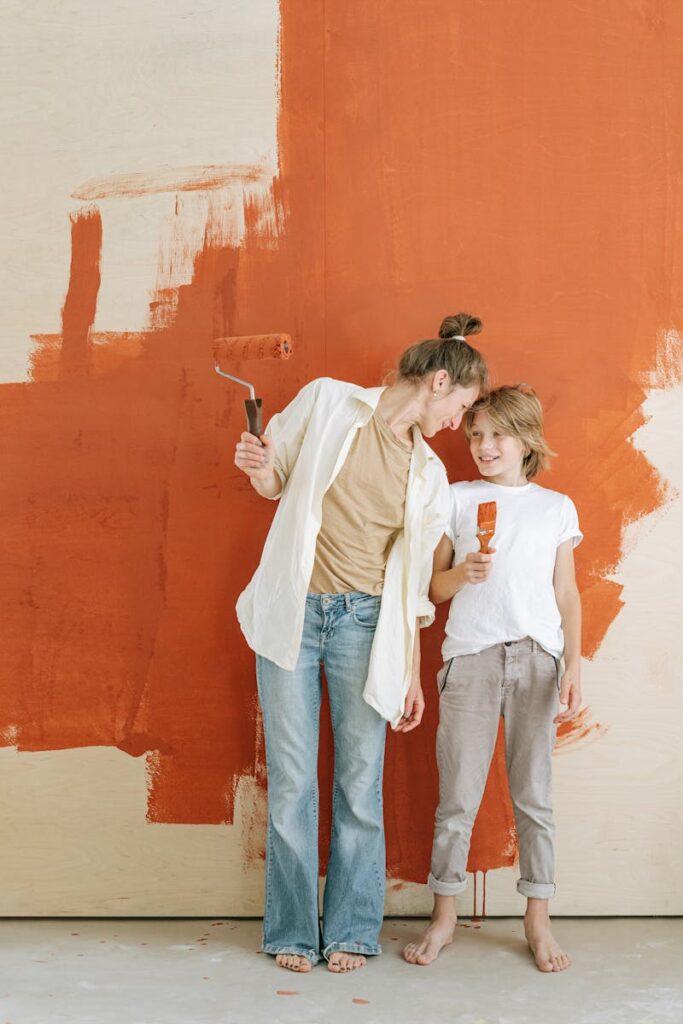 Mother and son smiling while painting a wall together in a home renovation project.