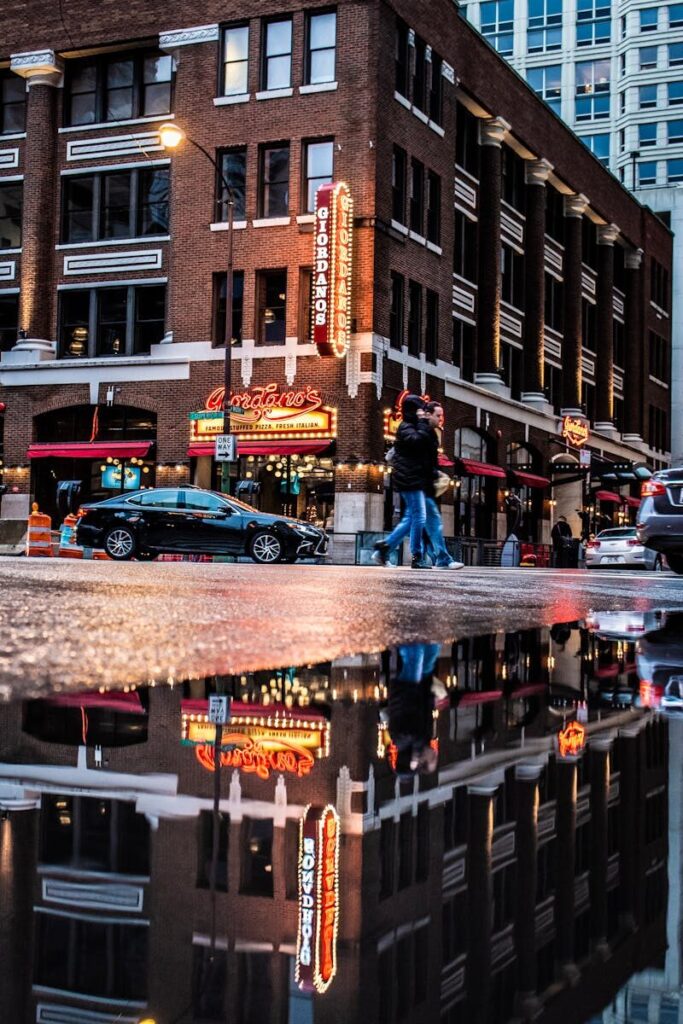 Photo by Cameron Casey Street scene in Chicago featuring a vibrant cityscape with reflections and night lights.