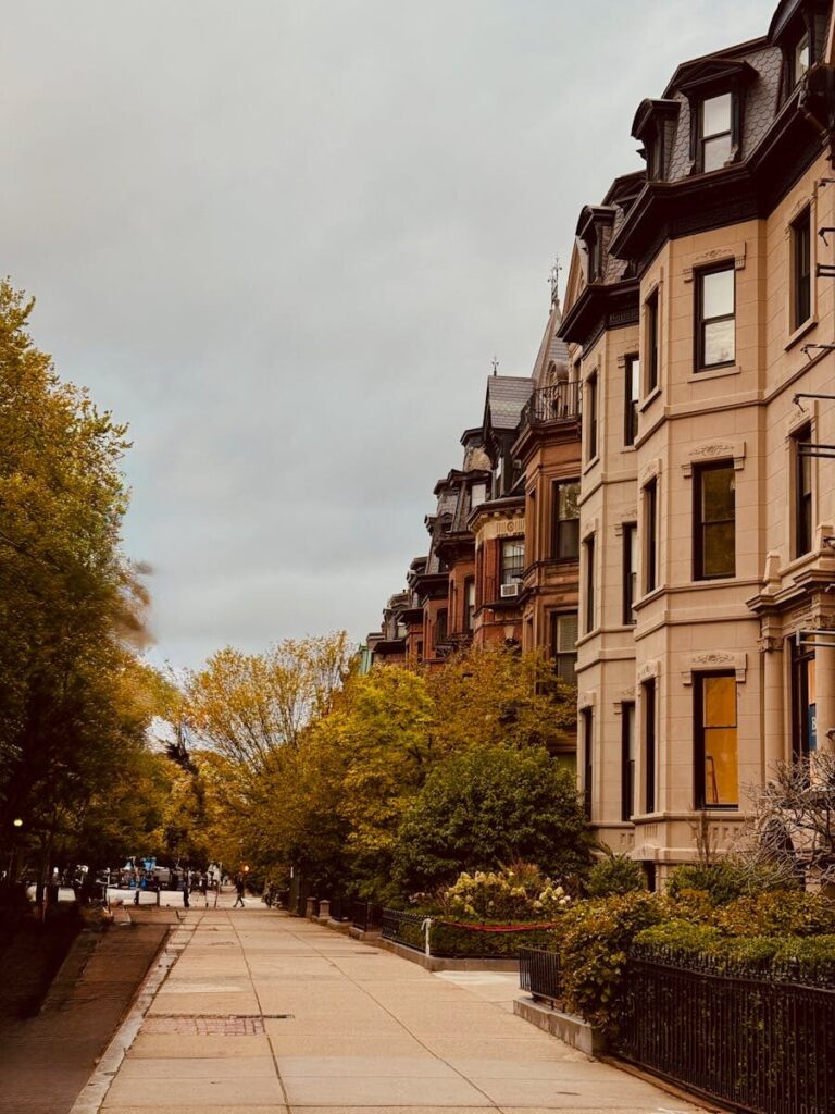 Photo by Teju Charming street view of brownstones and fall trees, perfect for architectural tours.