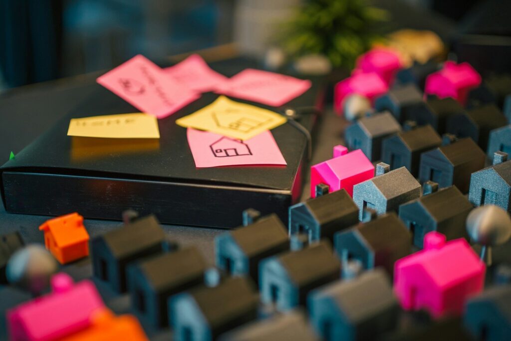 Photo by Jakub ลปerdzicki Miniature houses and notes on a dark table.